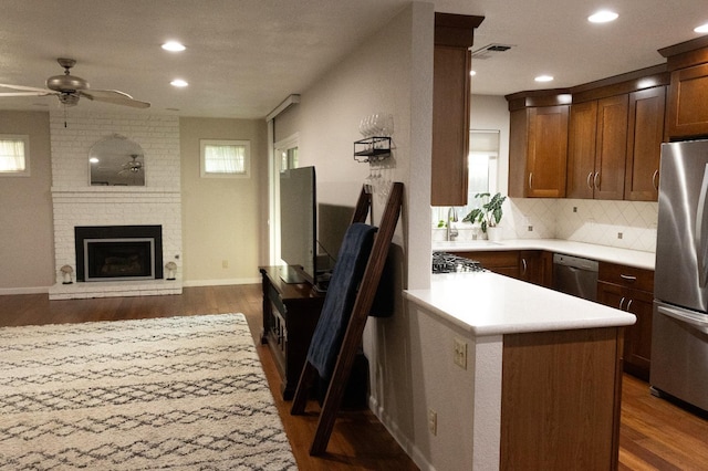 kitchen featuring ceiling fan, decorative backsplash, dark wood-type flooring, light countertops, and appliances with stainless steel finishes