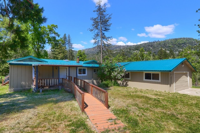 view of front facade featuring a front yard, a mountain view, and metal roof
