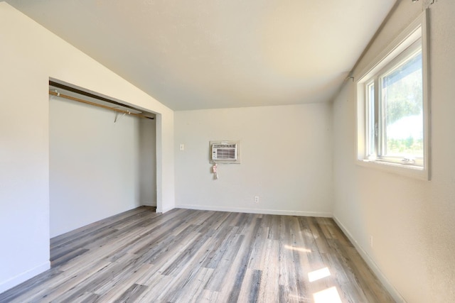 interior space with baseboards, a closet, light wood-style flooring, and a wall mounted AC