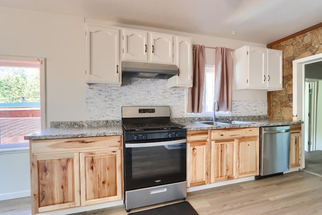 kitchen with a sink, stainless steel appliances, under cabinet range hood, a wealth of natural light, and light wood-style floors