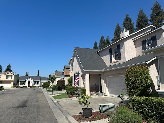 exterior space featuring a residential view, concrete driveway, a garage, stucco siding, and a chimney