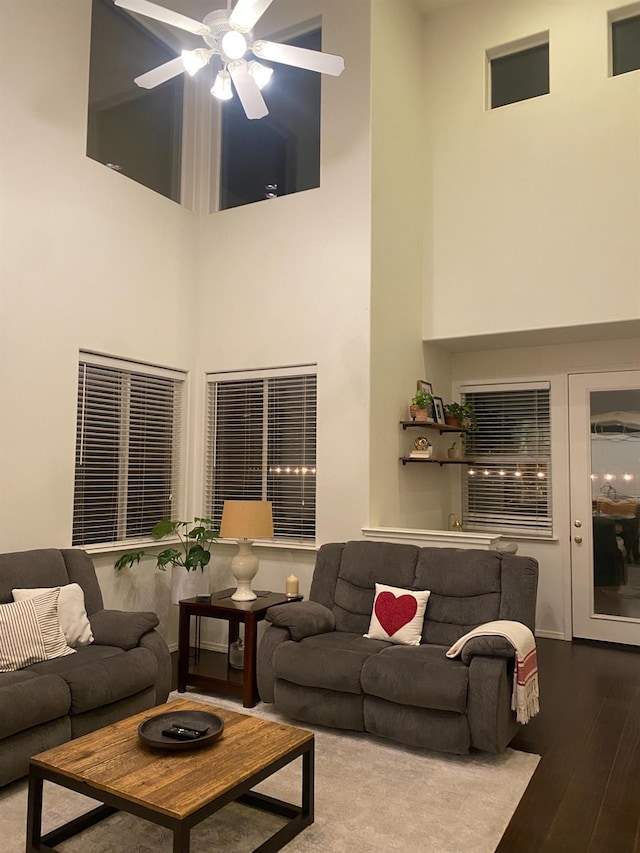 living area featuring a high ceiling, a ceiling fan, and wood finished floors