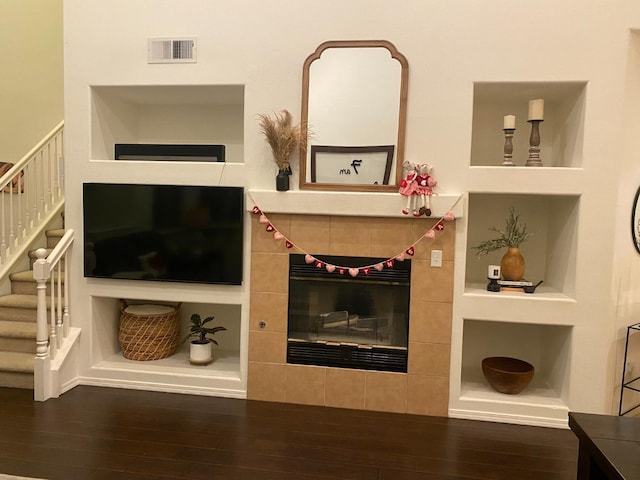 living area featuring built in shelves, stairs, visible vents, and wood finished floors
