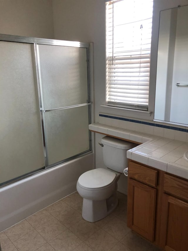full bath featuring toilet, vanity, and combined bath / shower with glass door