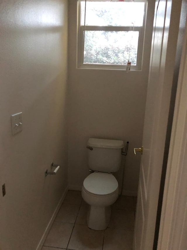 bathroom with toilet, baseboards, and tile patterned floors
