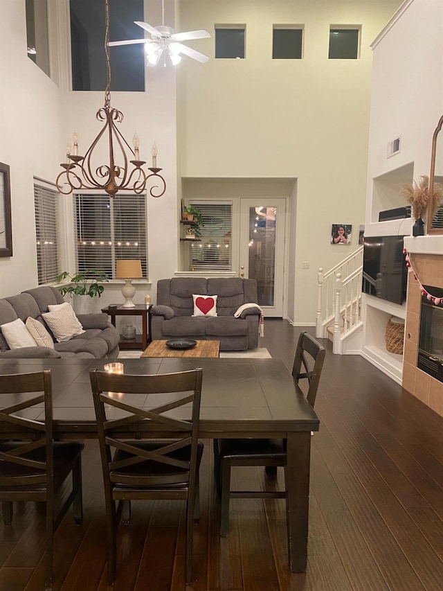 dining space with ceiling fan, visible vents, a towering ceiling, and hardwood / wood-style floors
