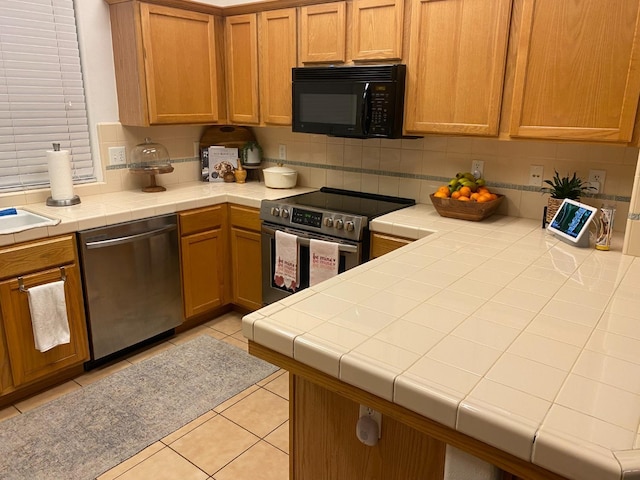 kitchen with stainless steel appliances, tasteful backsplash, light tile patterned flooring, and tile counters