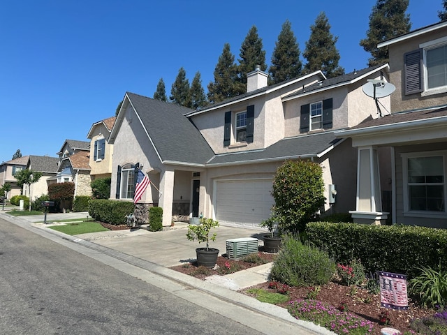 view of front facade with a garage, stucco siding, a chimney, and driveway