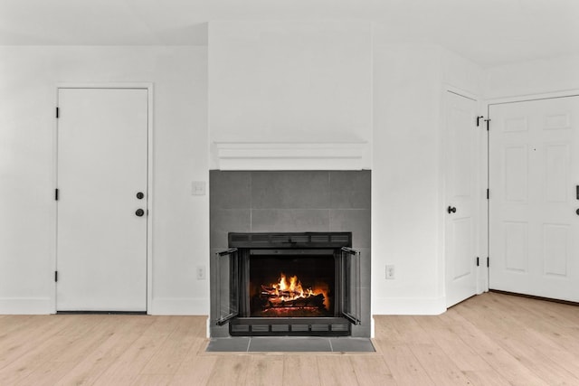 room details with baseboards, a tiled fireplace, and wood finished floors