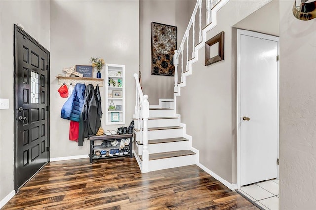 entrance foyer with wood finished floors, baseboards, and stairs