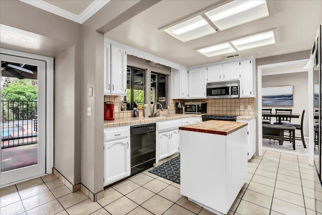 kitchen featuring black dishwasher, butcher block countertops, stainless steel microwave, and white cabinets