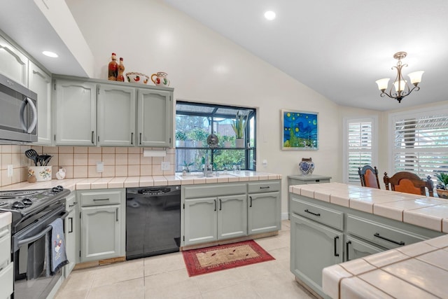 kitchen featuring black dishwasher, a notable chandelier, stainless steel microwave, lofted ceiling, and range with electric stovetop