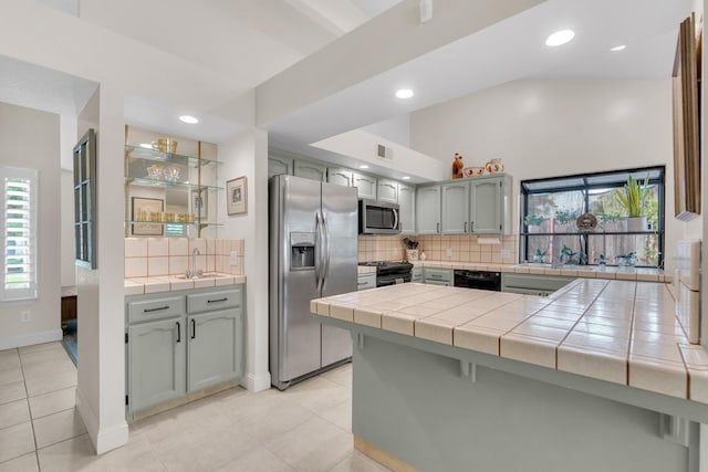kitchen with a peninsula, light tile patterned flooring, black appliances, visible vents, and backsplash
