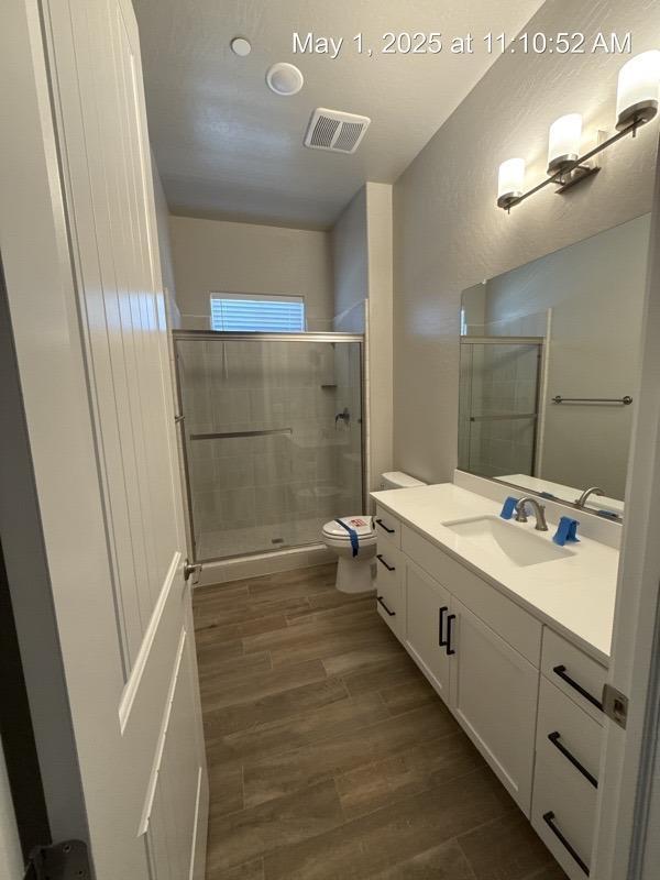 1765 N Whitmore, Clovis, CA 93619 - full bath with toilet, a shower stall, visible vents, and wood finished floors