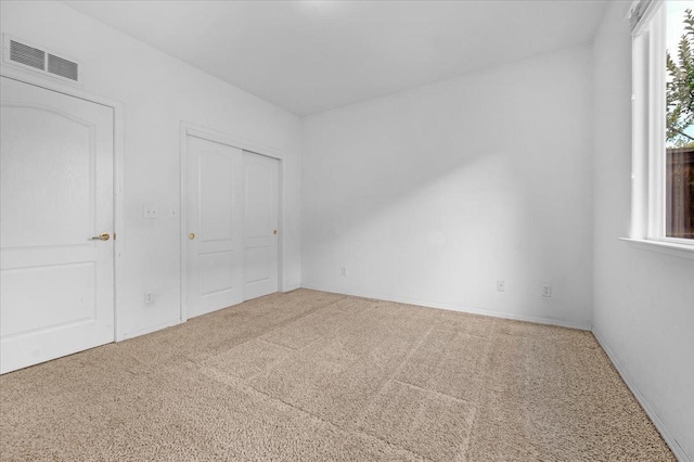 unfurnished bedroom with carpet flooring, a closet, and visible vents