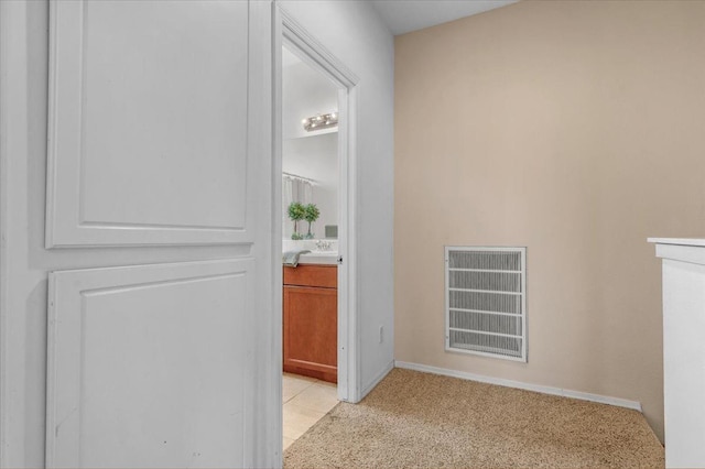 hall with light colored carpet, light tile patterned flooring, and visible vents