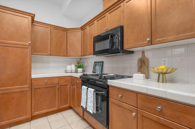 kitchen with backsplash, tile countertops, black appliances, and brown cabinets