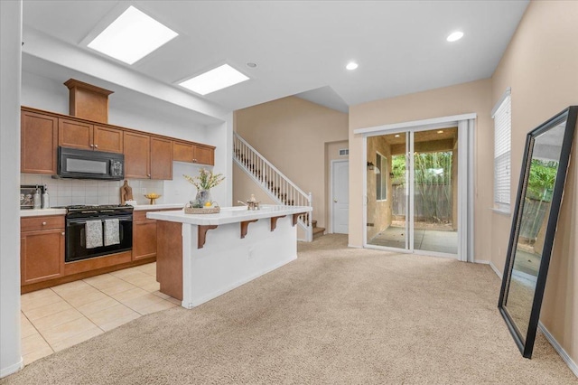 kitchen featuring light colored carpet, brown cabinetry, light countertops, and black appliances