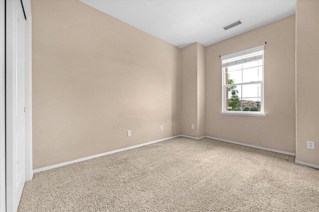 carpeted empty room with visible vents and baseboards