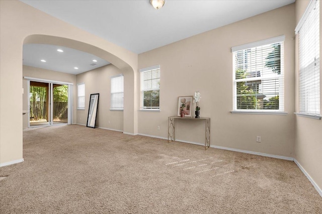 unfurnished room featuring baseboards, recessed lighting, carpet floors, and arched walkways