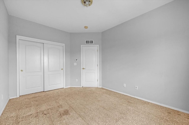 unfurnished bedroom with carpet, a closet, baseboards, and visible vents