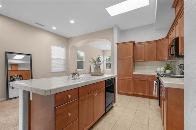 kitchen featuring tile countertops, visible vents, a sink, arched walkways, and black appliances