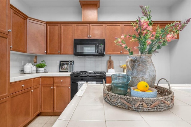 kitchen with backsplash, tile countertops, black appliances, and light tile patterned floors