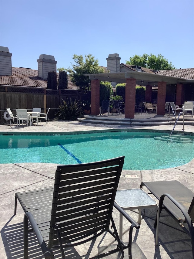 pool with a patio area and fence