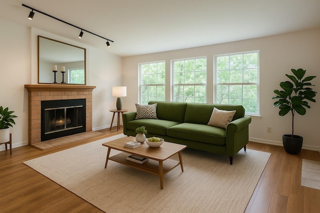 7093 N Teilman Unit 102, Fresno, CA 93711 - living room featuring rail lighting, wood finished floors, baseboards, and a brick fireplace