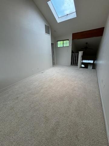 unfurnished living room with a skylight, carpet floors, high vaulted ceiling, and visible vents