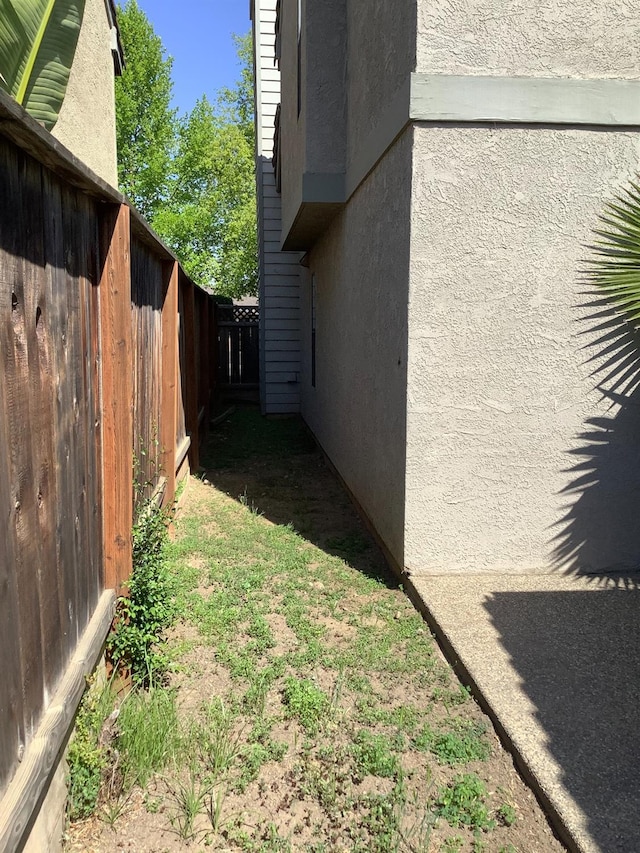 view of side of property with fence and stucco siding