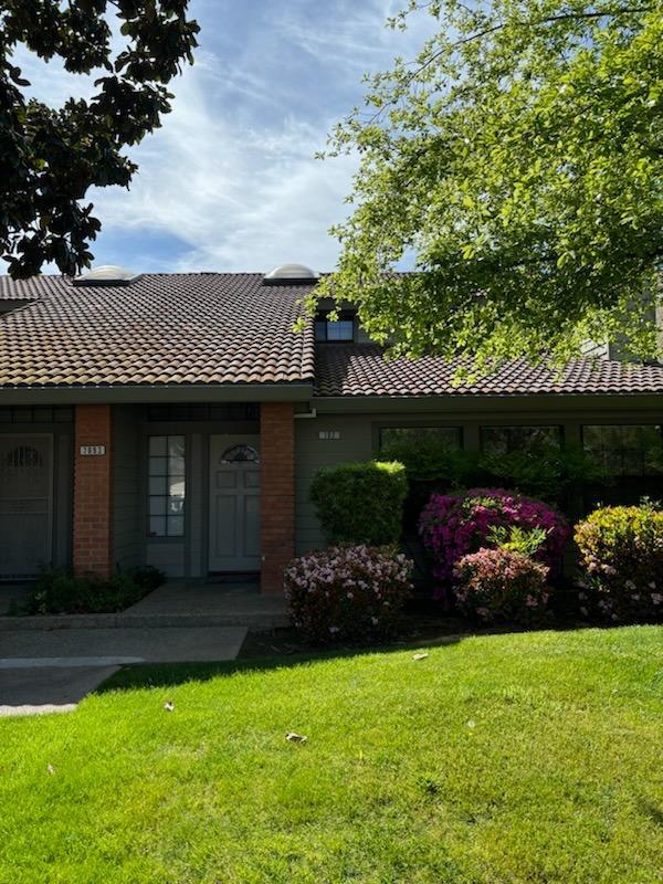 view of front facade featuring a chimney, a front yard, brick siding, and a tile roof