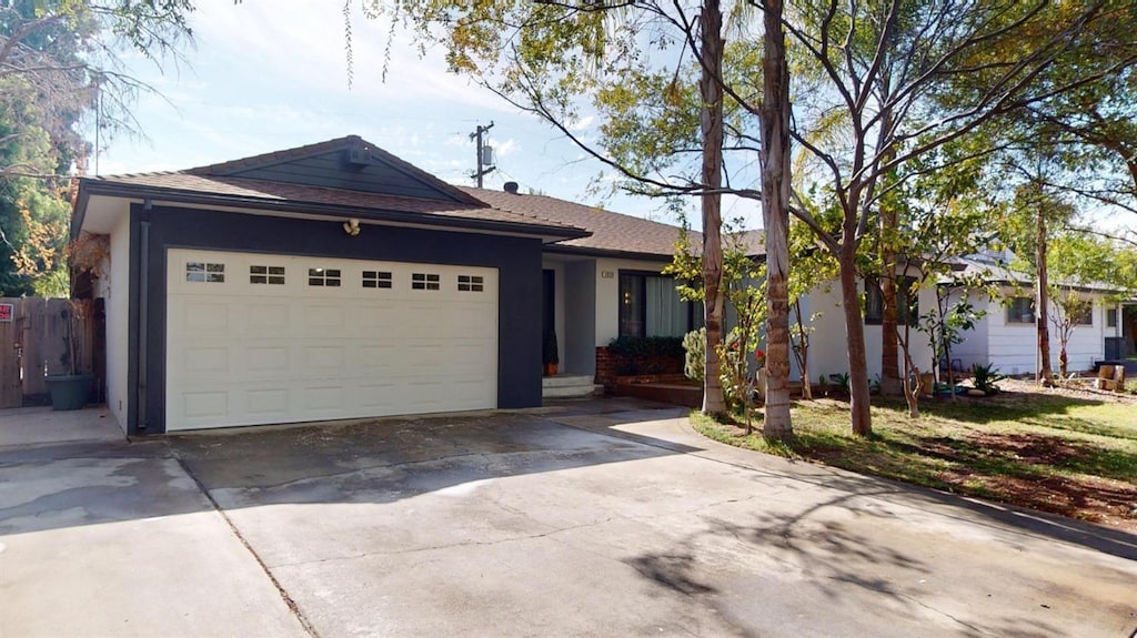 ranch-style home featuring roof with shingles, a garage, stucco siding, and driveway