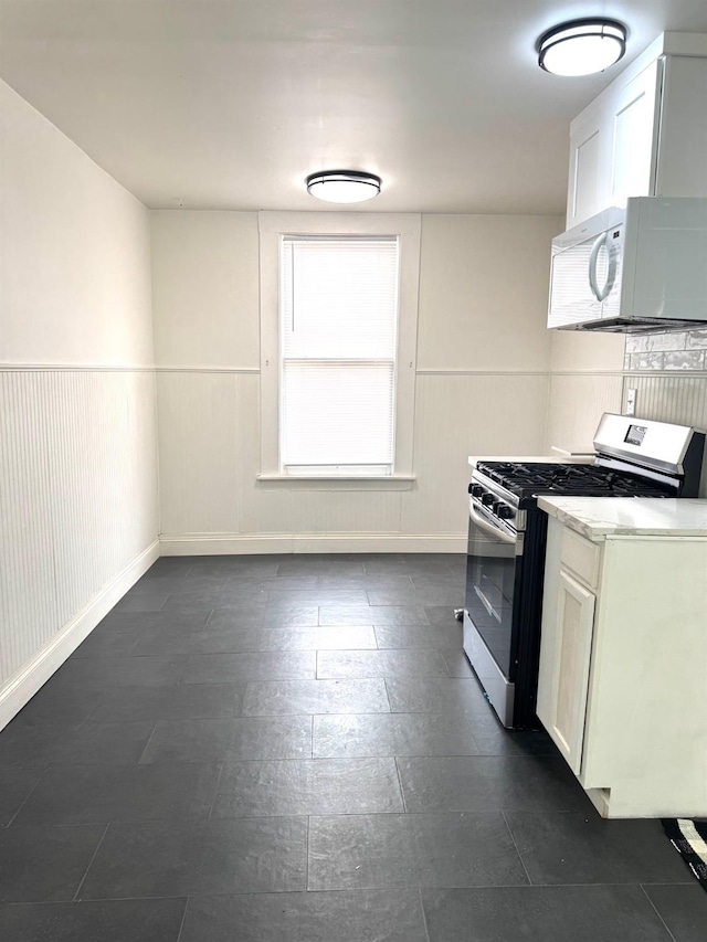 220 S K, Madera, CA 93637 - kitchen with white cabinets, stainless steel gas range, baseboards, and white microwave