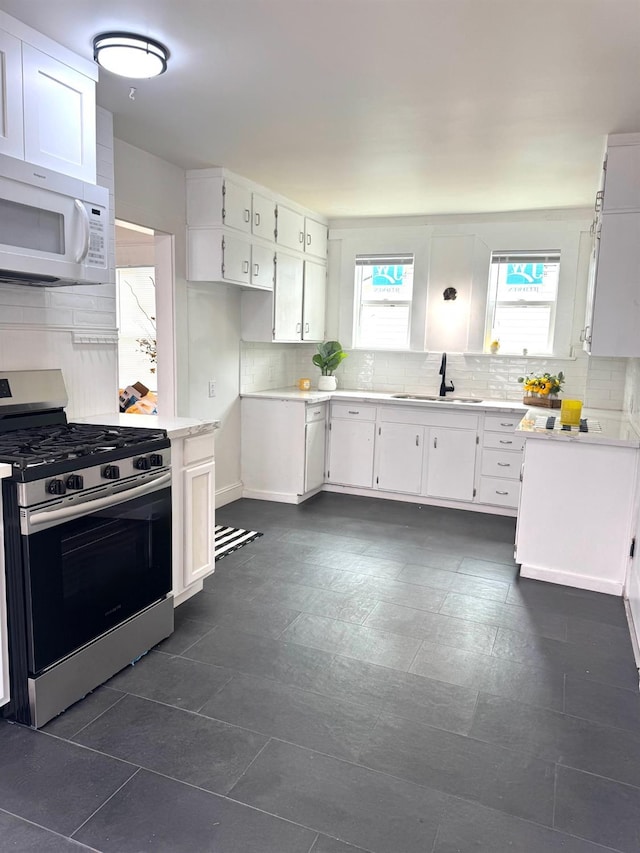 220 S K, Madera, CA 93637 - kitchen featuring stainless steel gas range, backsplash, white microwave, and white cabinetry