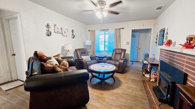 living area with a ceiling fan, visible vents, and wood finished floors