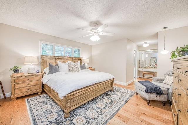 bedroom featuring a textured ceiling, light wood-style flooring, and baseboards