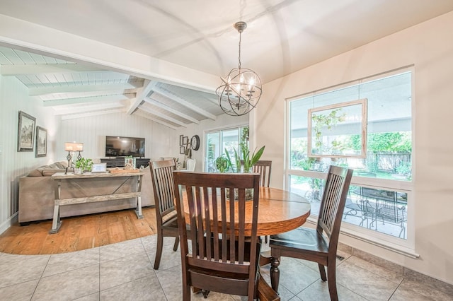 dining space featuring an inviting chandelier, light tile patterned flooring, and lofted ceiling with beams