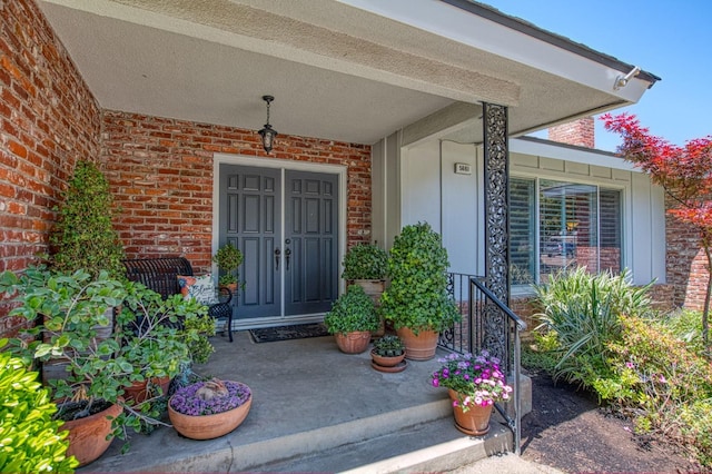 property entrance with covered porch and brick siding