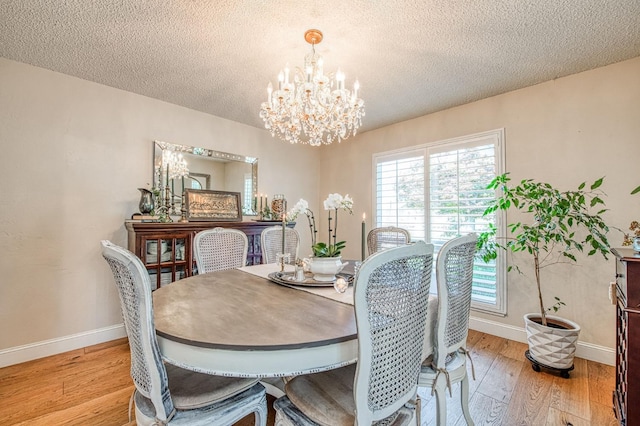 dining room with baseboards, an inviting chandelier, a textured ceiling, and wood finished floors