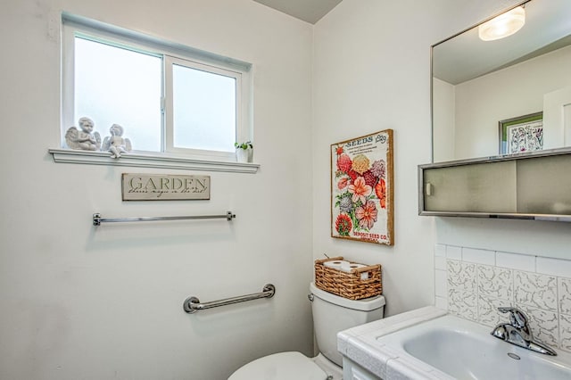 half bath with backsplash, toilet, and a sink
