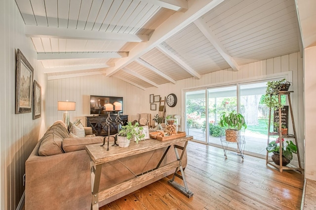 living area featuring lofted ceiling with beams, wooden walls, and light wood-style flooring