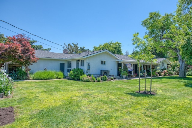 back of house featuring a yard, stucco siding, and a chimney