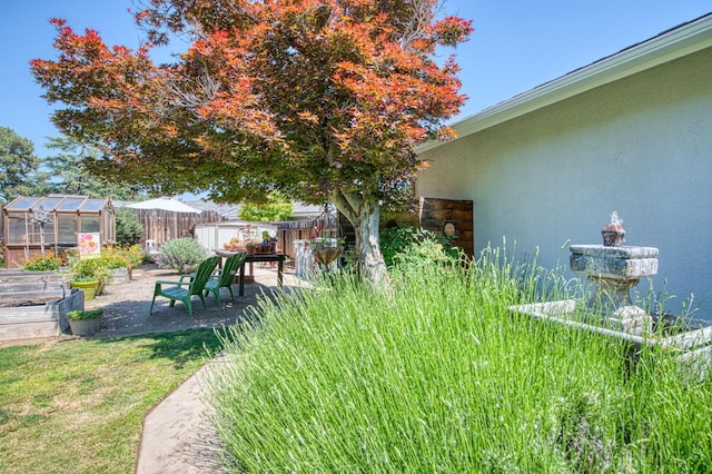 view of yard with a vegetable garden, an outdoor structure, a greenhouse, and a fenced backyard