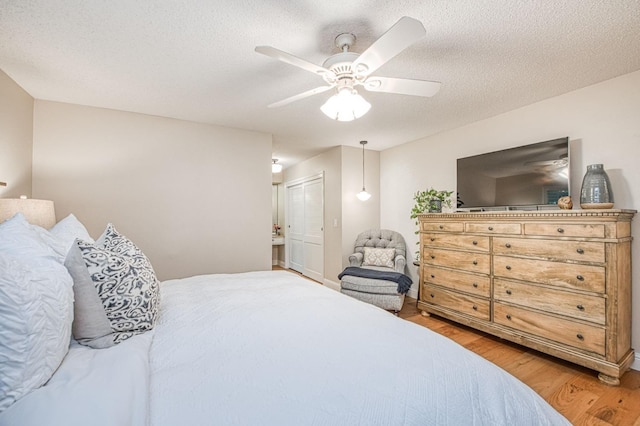 bedroom with light wood finished floors, a textured ceiling, and a ceiling fan