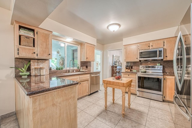 kitchen with stainless steel appliances, light brown cabinetry, a sink, and decorative backsplash
