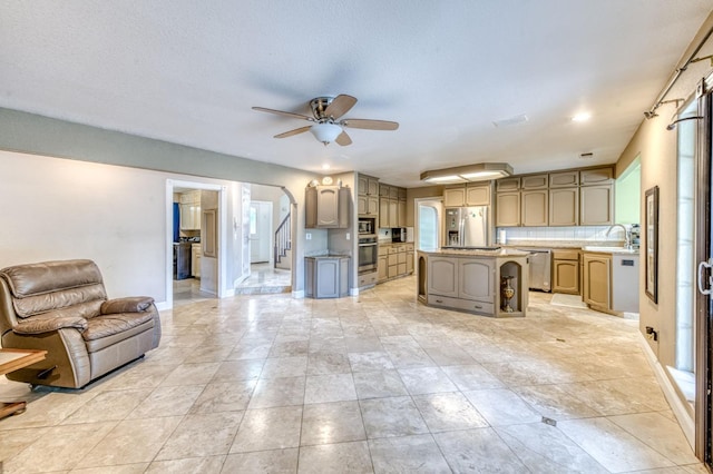 8164 N 8th St, Fresno, CA 93720 - kitchen with arched walkways, open floor plan, a ceiling fan, a kitchen island, and appliances with stainless steel finishes