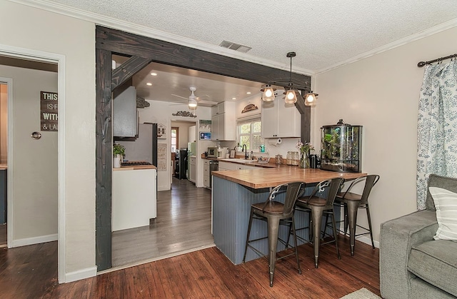 528 W Yale Ave, Fresno, CA 93705 - kitchen with butcher block counters, dark wood-type flooring, visible vents, crown molding, and white cabinets