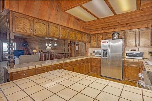 39090 Woodland Rd, Shaver Lake, CA 93664 - kitchen with appliances with stainless steel finishes, a peninsula, tile counters, brown cabinets, and wood walls