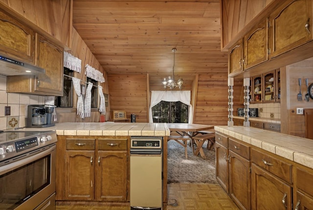 39090 Woodland Rd, Shaver Lake, CA 93664 - kitchen with stainless steel electric range oven, a peninsula, a chandelier, brown cabinets, and wood walls